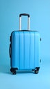 Bright blue wheeled suitcase with telescopic handle against a plain light blue background Royalty Free Stock Photo