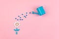 Bright blue and white pills and tablets in flower shape and garden watering can on pink background. Medicines, drugs, pharmacy