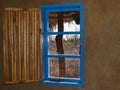 Bright blue window with open slat slat wooeden shutter and view Royalty Free Stock Photo