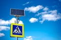 Bright blue and yellow pedestrian crosswalk sign with traffic warning. Powered by solar energy with its own solar panel Royalty Free Stock Photo