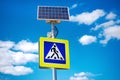 Bright blue and yellow pedestrian crosswalk sign with traffic warning. Powered by solar energy with its own solar panel Royalty Free Stock Photo