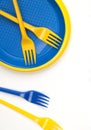 Bright blue and yellow plastic disposable tableware on white background close-up