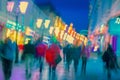 Bright blurred modern city at night, defocused urban bokeh city lights, silhouettes of the walking people. Abstract