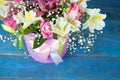 bright bouquet of alstroemeria, roses and greens on blue and white background