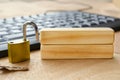 A bright brass padlock positioned on a desk near a computer keyboard with blank wooden blocks with customizable space for text Royalty Free Stock Photo