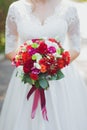 Bright bridal summer delicate bouquet of flowers of red, burgundy, orange and white roses, green leaves and red berries.
