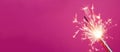 Bright burning sparkler stick on pink background banner. Generate ai
