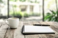 A bright cafÃ© provides the backdrop for a cozy workspace setup complete with a blank notebook, pen, and a steaming cup Royalty Free Stock Photo
