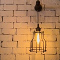 bright caged steel lamp shining on a brick wall Royalty Free Stock Photo