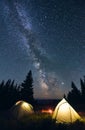 Bright campfire and tents in night forest. Royalty Free Stock Photo