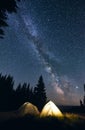 Bright campfire and tents in night forest. Royalty Free Stock Photo