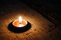 Bright candle on wood in night.