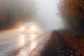 bright car headlights approaching on a misty autumn road Royalty Free Stock Photo