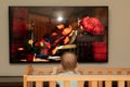 Bright cartoons fascinate a small child when he looks at the screen