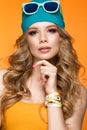 Bright cheerful girl in sports hat, colorful make-up, curls and pink manicure. Beauty face.