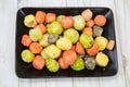 Bright cheese balls mix on a black rectangular plate with a wooden table background. Food is a delicacy snack Royalty Free Stock Photo