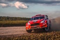 Bright cherry red vehicle on a dirt road during a race competition