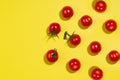 Bright cherry tomatoes in hard light with shadow on yellow background, flat lay, border, copy space. Food colorful pattern