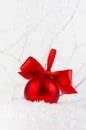 Bright christmas background - elegant festive shiny red ball with satin ribbon in decorative fairy white winter forest with frosty