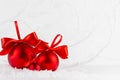 Bright christmas background - three elegant glossy red balls with satin ribbon closeup in decorative fairy white winter forest. Royalty Free Stock Photo