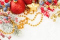 Bright Christmas composition with red baubles, holly berries, Xmas tree branch and golden garland on white snow background Royalty Free Stock Photo
