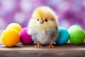 Bright close-up. Adorable yellow chicken on a wooden table surrounded by Easter eggs