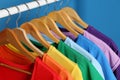 Bright clothes on hangers against blue background. Rainbow colors