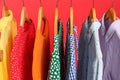Bright clothes on hangers against red background. Rainbow colors