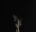 Bright cloud of smoke rise from lighter in dark environment with black background Royalty Free Stock Photo