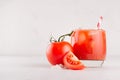 Bright cold red tomato cocktail bloody Mary in elegance glass with glossy tomato, salt, straw, ice, piece on white wooden board.