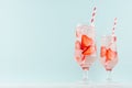 Bright cold strawberry cocktail with ripe red slices berry and sparkling water, ice cubes, red striped straw in misted glass.