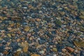 Bright colored blue small pebbles in clear water sparkles in sun, morning lake baikal Royalty Free Stock Photo