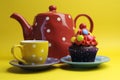 Bright colored candy cupcake with polka dot tea pot and cup.