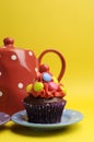 Bright colored candy cupcake with polka dot tea pot and cup - vertical.