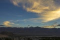 A bright colored clouds in a dark blue sky during sunset over the mountains with snow peaks Royalty Free Stock Photo