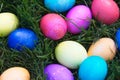 Bright colored Easter eggs piled in the green grass.