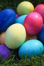 Bright colored Easter eggs piled in the green grass.