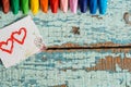 Bright colored pencils on an old blue green wooden background. Two red hearts painted on a slice of paper Royalty Free Stock Photo