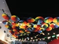 Bright colored umbrellas, painted in all the primary colors of the palette, against the background of the dark night sky
