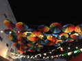 Bright colored umbrellas, painted in all the primary colors of the palette, against the background of the dark night sky