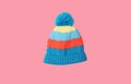 Bright colorful blue baby knitted winter hat isolated on pink background