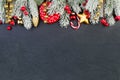 Bright colorful Christmas border with Xmas decor on black background. Green Xmas tree twig, red glass balls, berries, candy food Royalty Free Stock Photo