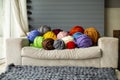 Bright colorful colored balls of merino wool on the sofa near the window with a gray plaid on a sunny day. Royalty Free Stock Photo