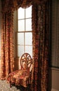 Beautiful chair covered with the same fabric as drapes in well-lit room of home Royalty Free Stock Photo
