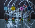 Bright and colorful lollipop and candies in bottles standing on the glass table in the dark on background of lines of light. Royalty Free Stock Photo