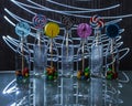 Bright and colorful lollipop and candies in bottles standing on the glass table in the dark on background of lines of light. Royalty Free Stock Photo