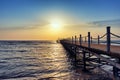 Bright and colorful sunrise over the pier and sea. Perspective view of wooden pier on the sea at sunrise with rocky Royalty Free Stock Photo