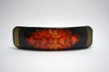 Bright colorful wooden hairpin with Ukrainian Petrikov painting in orange colors located on a white background.