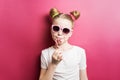 Bright colors: a girl with a striped lollipop and sunglasses on a bright pink background. Royalty Free Stock Photo