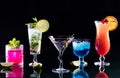 Bright colourful cocktails in a row, against a black background.